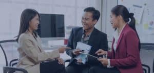 Three business professionals discuss documents in an office