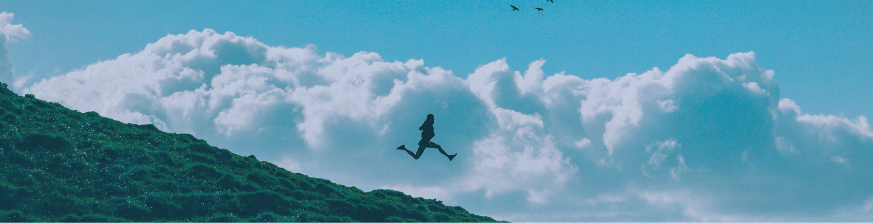 Siluet seorang pemimpin melompat di atas bukit hijau dengan latar belakang langit biru dan awan, melambangkan semangat dan keberanian dalam leadership excellence.